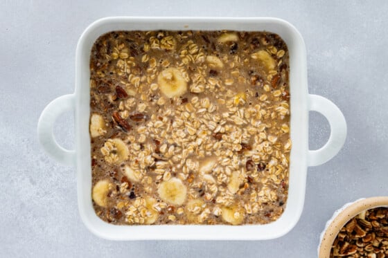 Unbaked baked oatmeal mixture in a white square baking dish.