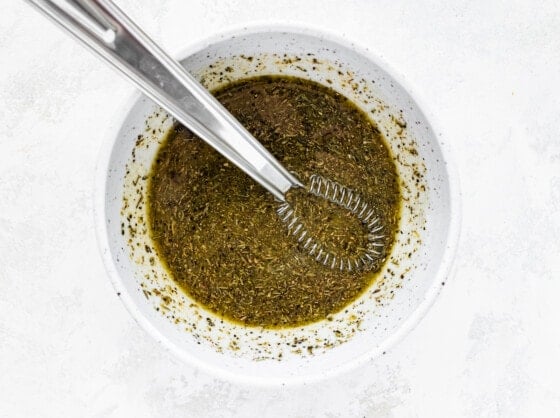 A metal whisk in a bowl of marinade.