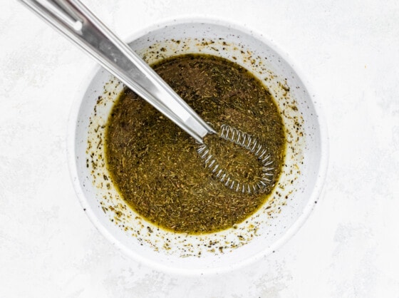 A metal whisk in a bowl of marinade.