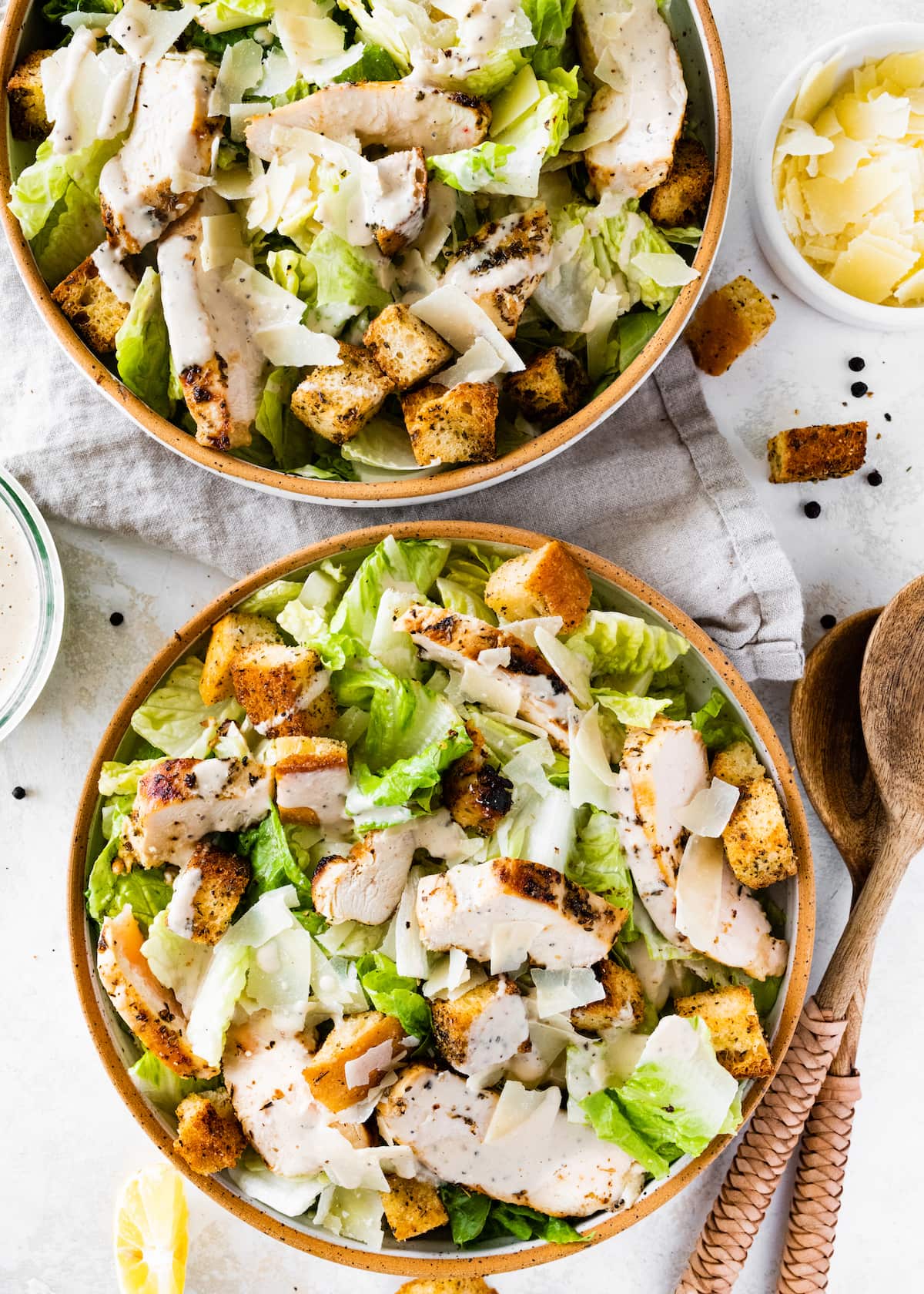 Grilled chicken caesar salad in two separate bowls.