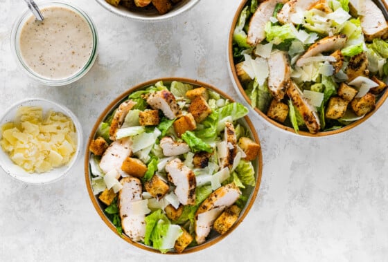 Grilled chicken Caesar salad in two separate bowls.