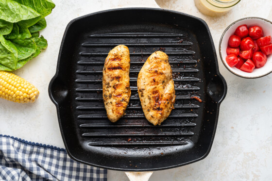 Two grilled chicken breasts on a grill pan.