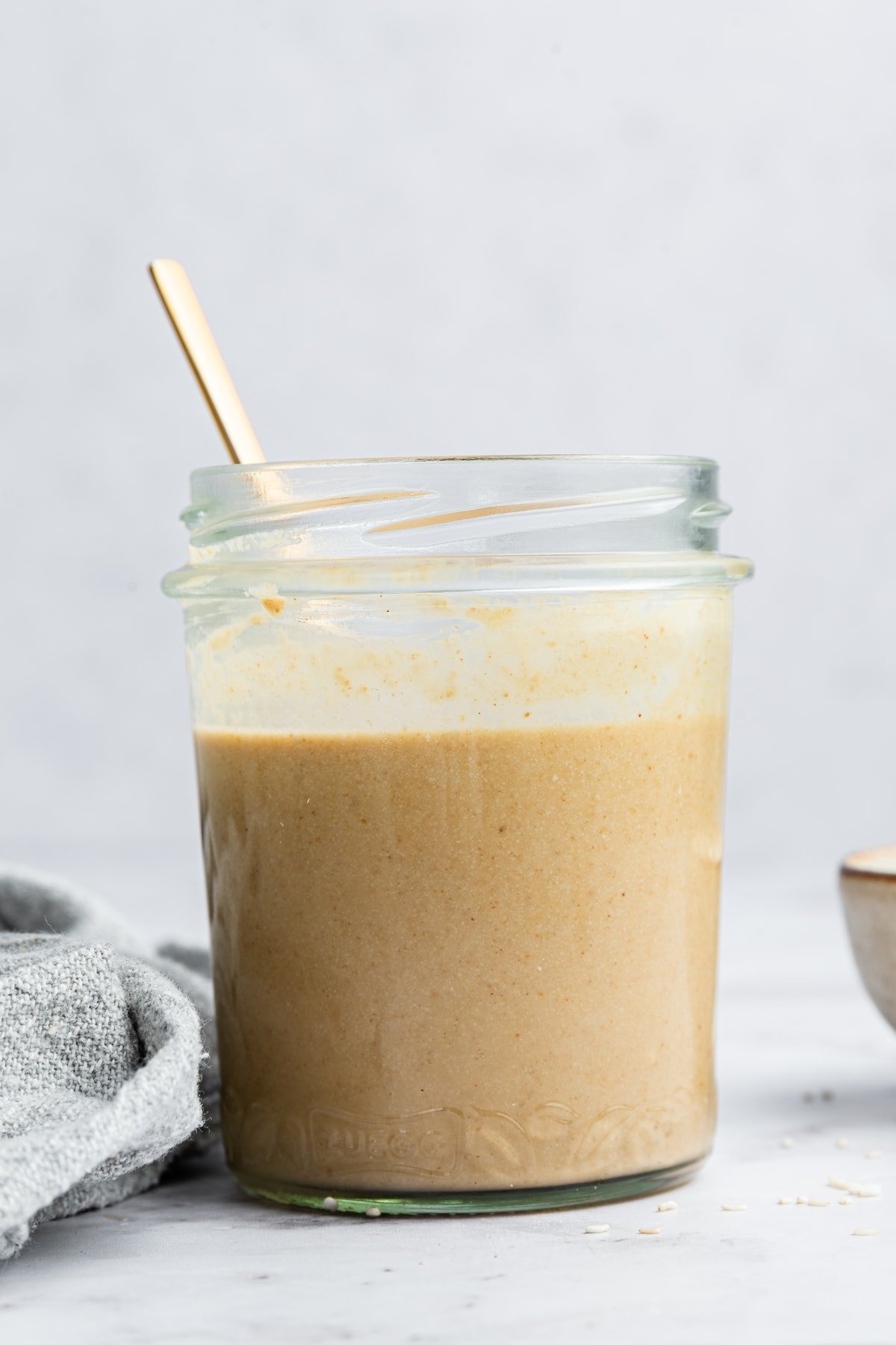 Tahini in a glass mason jar with a spoon inside.