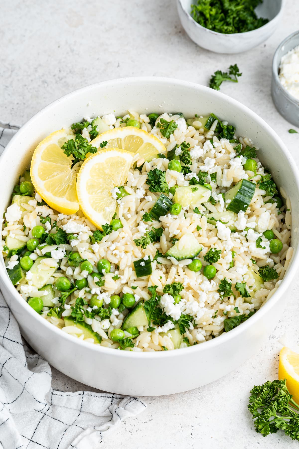 Lemon orzo salad with fresh lemon slices in a white bowl.