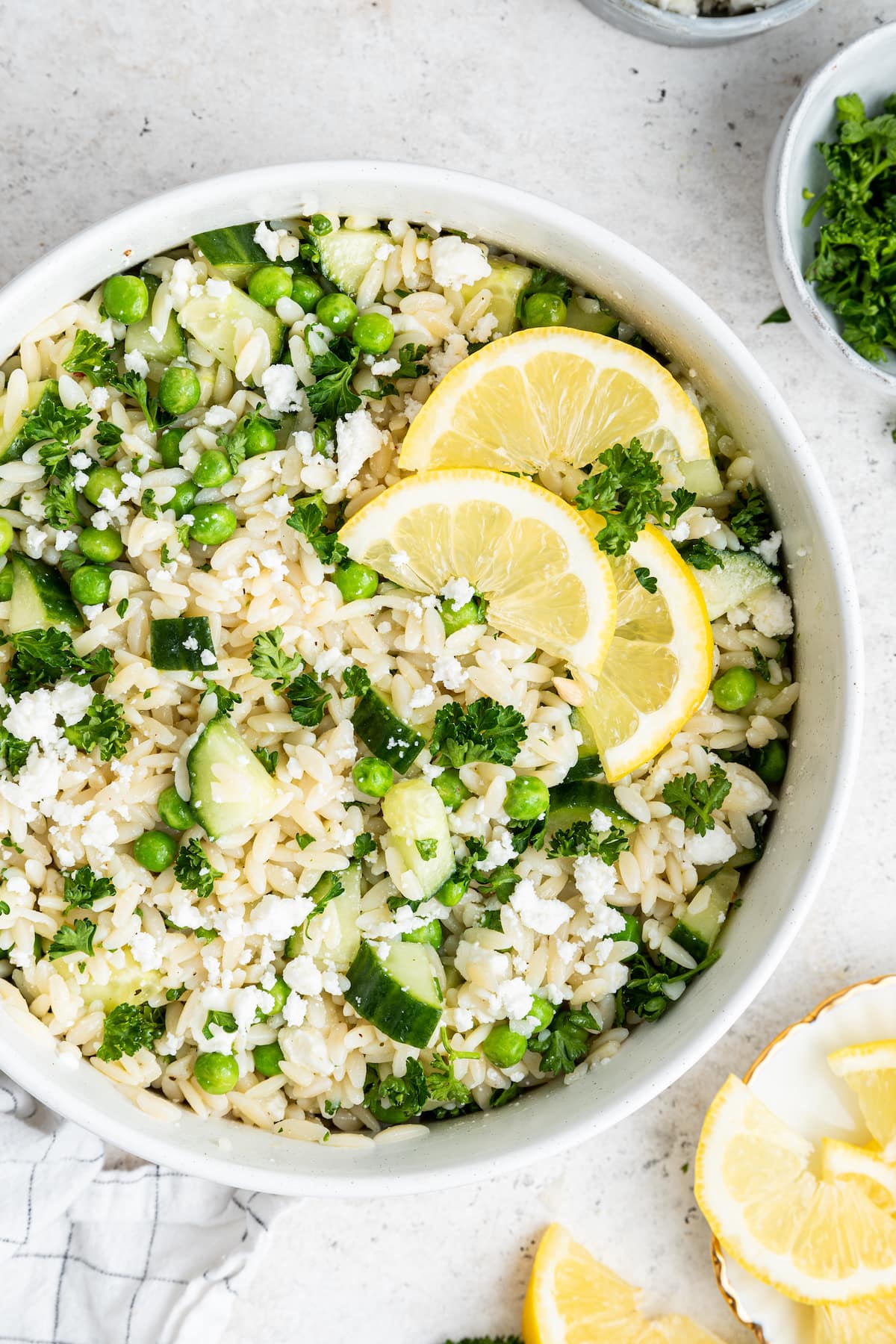 Lemon orzo salad with fresh lemon slices in a white bowl.