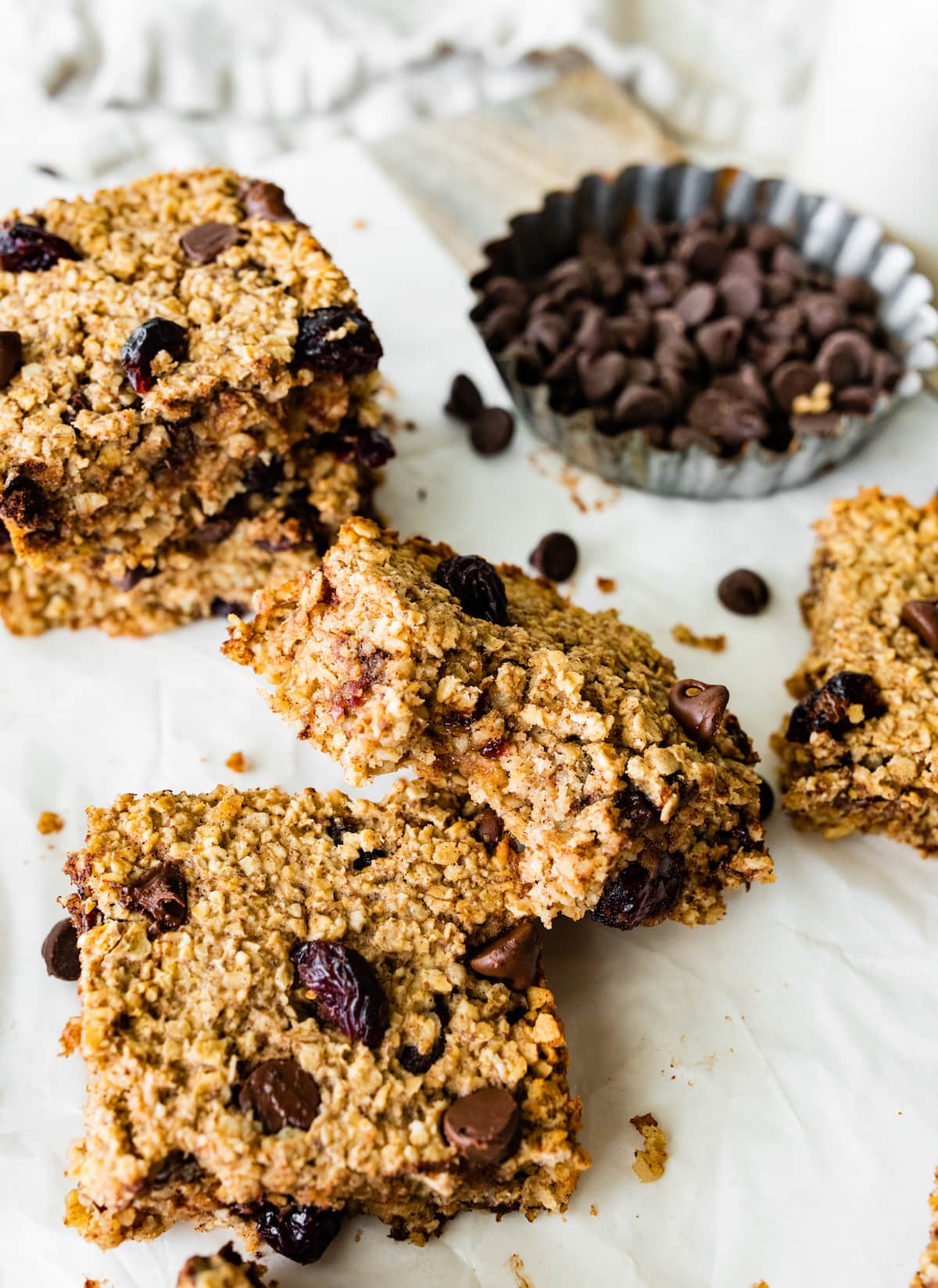 Multiple oatmeal breakfast bars on parchment paper with one bar that has a bite taken from it.