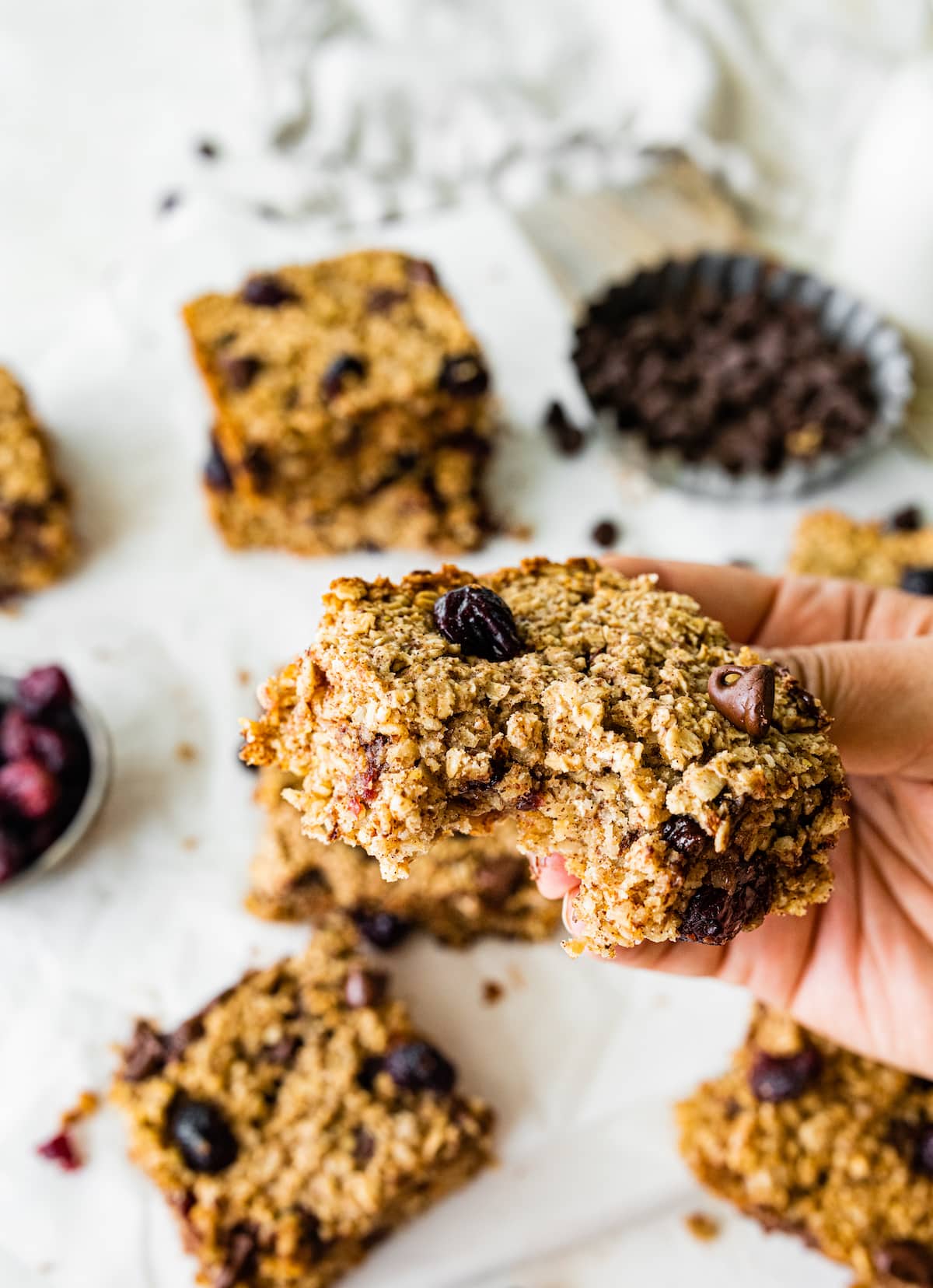 A woman's hand holding a oatmeal breakfast bar with a bite taken from it.