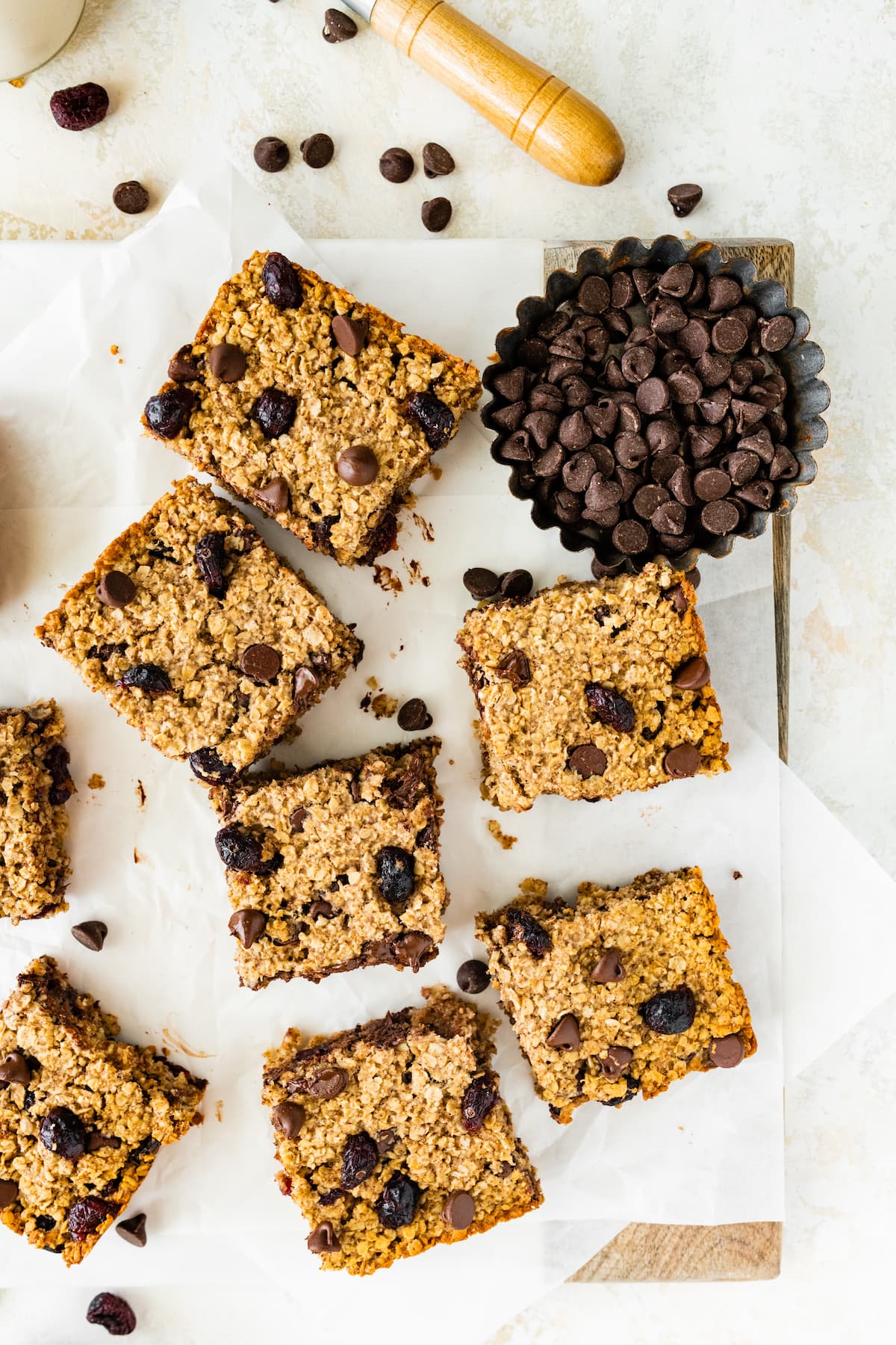 Oatmeal breakfast bars on parchment paper, on a wooden cutting board.