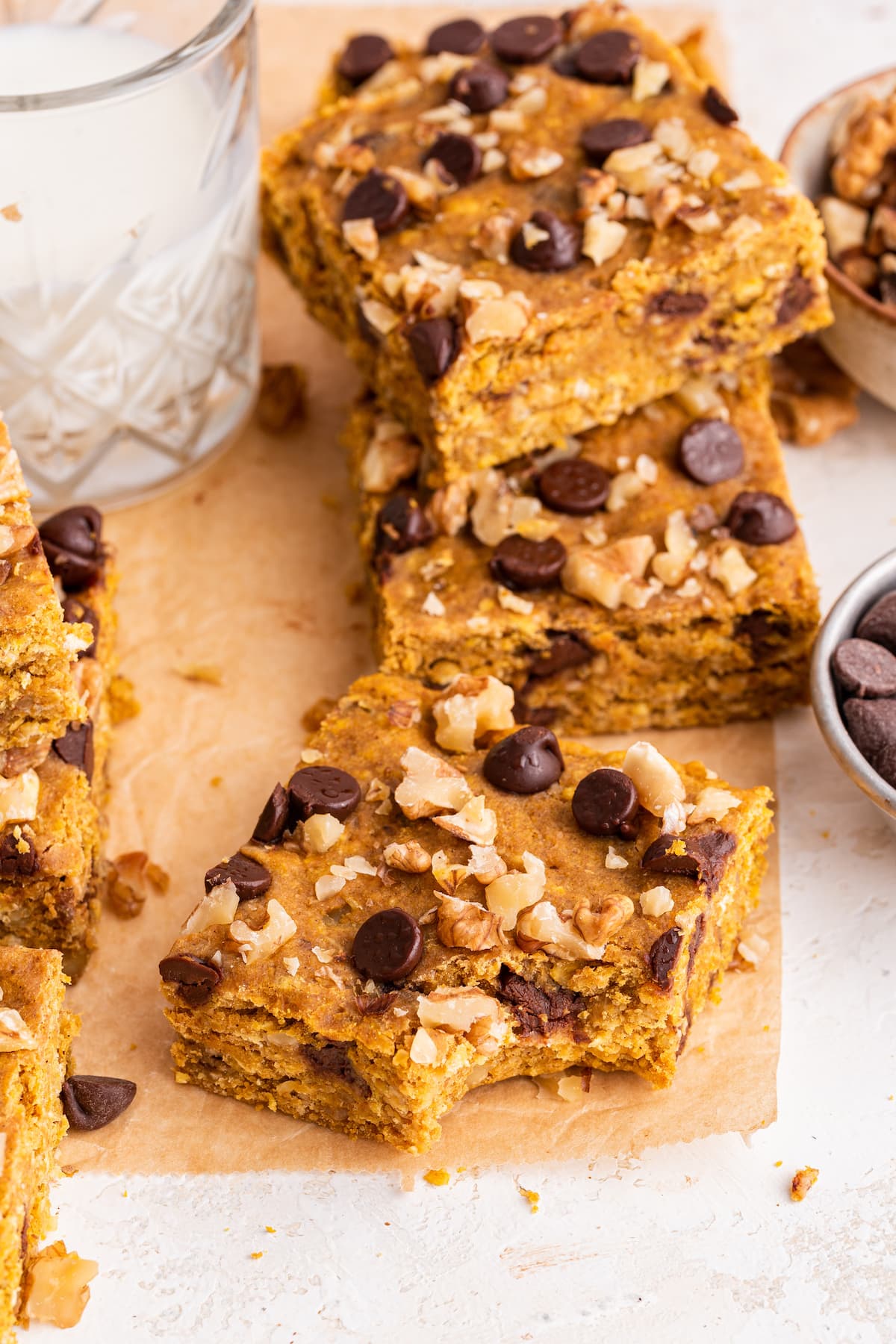 Pumpkin oatmeal bars on parchment paper with one bar having a bite taken out of it.