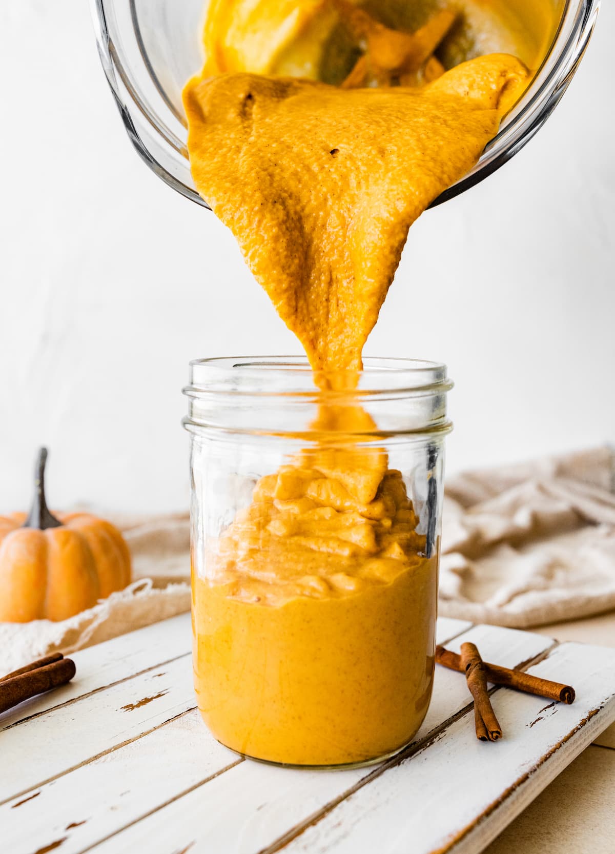 Pouring the pumpkin protein shake from a blender into a glass mason jar.