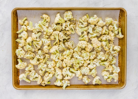 Cauliflower florets on a baking tray before being roasted.