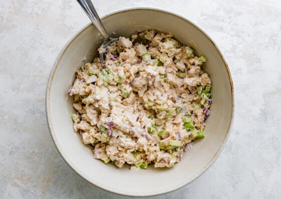 Rotisserie chicken salad in a large bowl with a metal spoon.