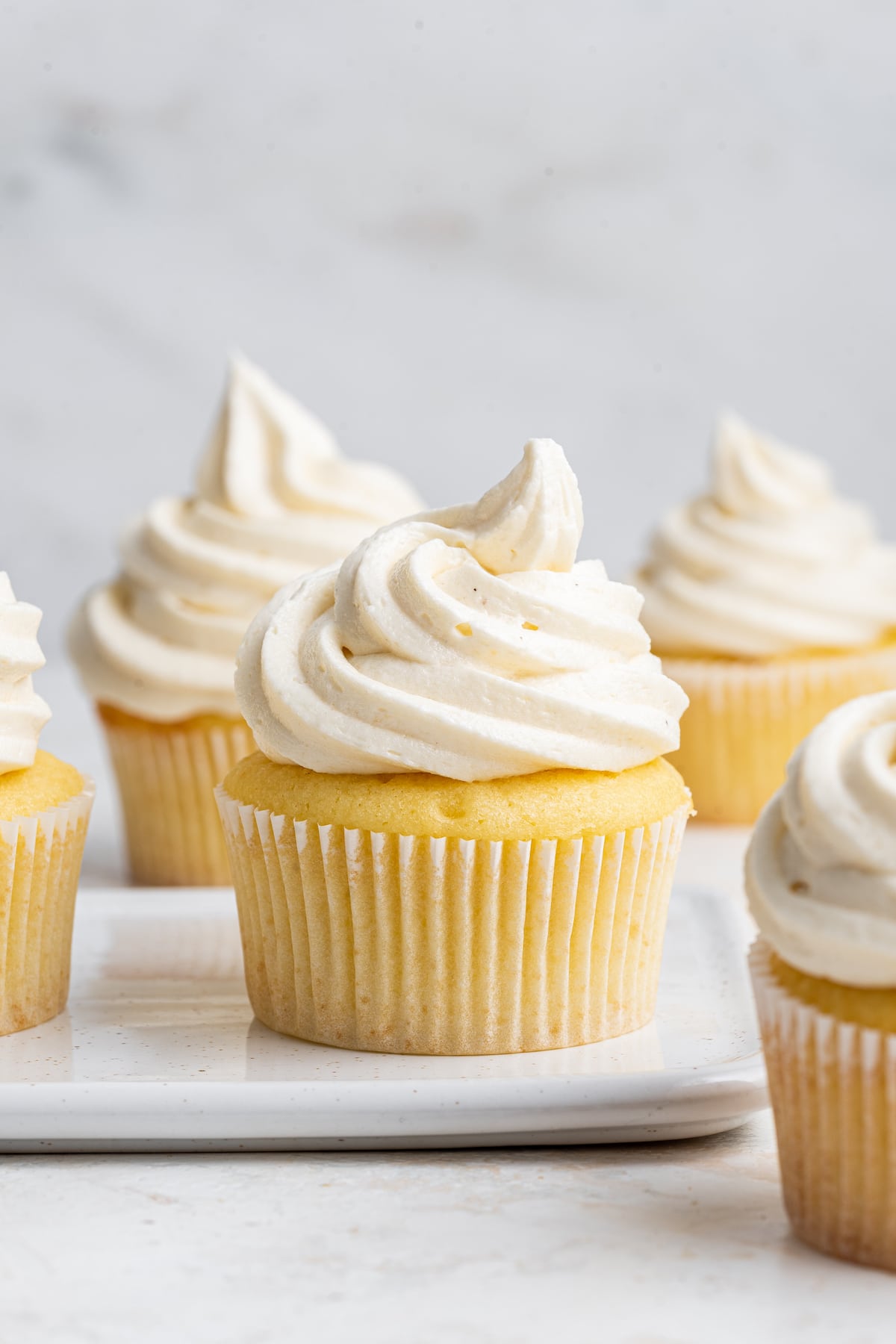 Multiple cupcakes with vanilla buttercream frosting.