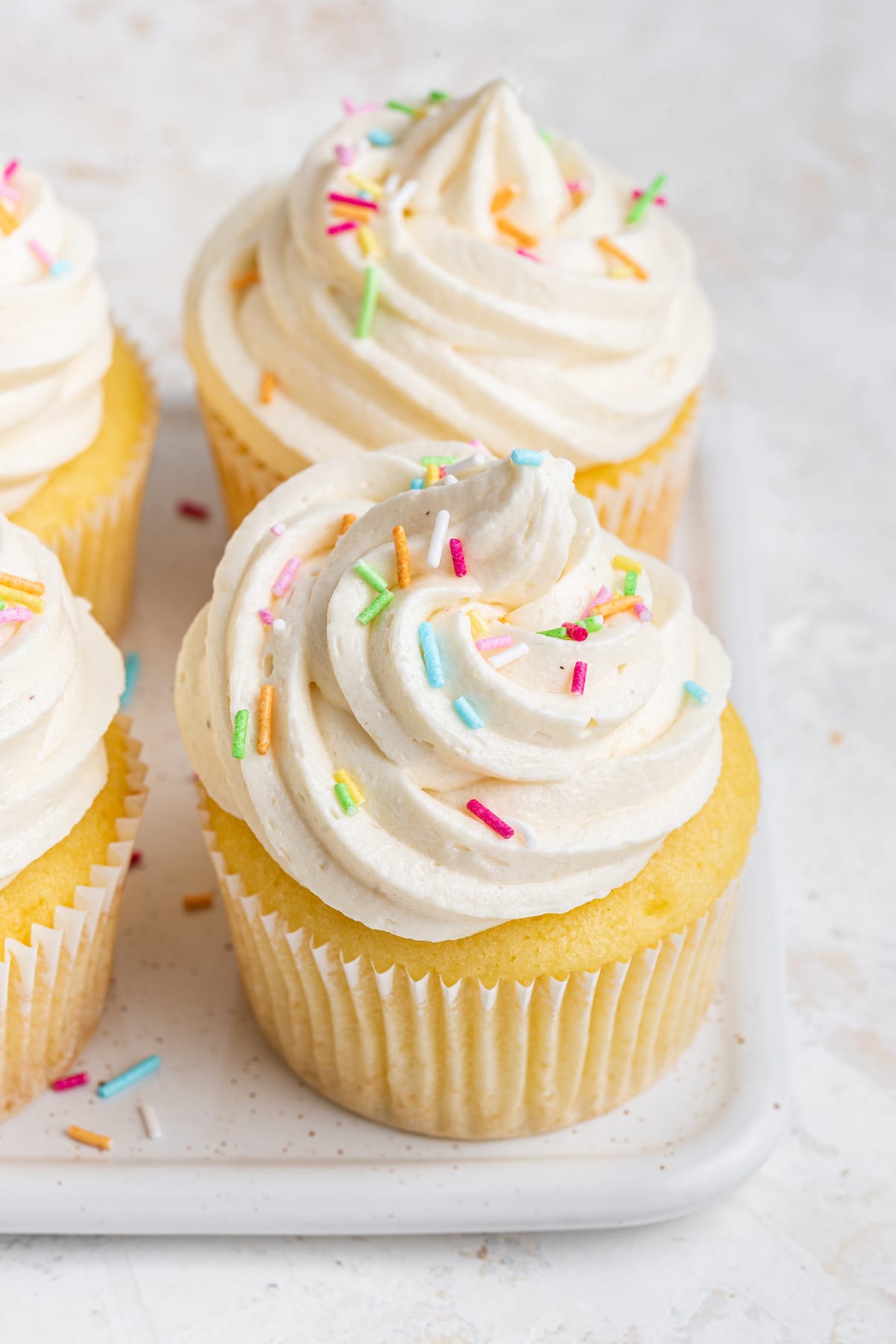 Cupcakes with vanilla buttercream frosting and sprinkles on top.