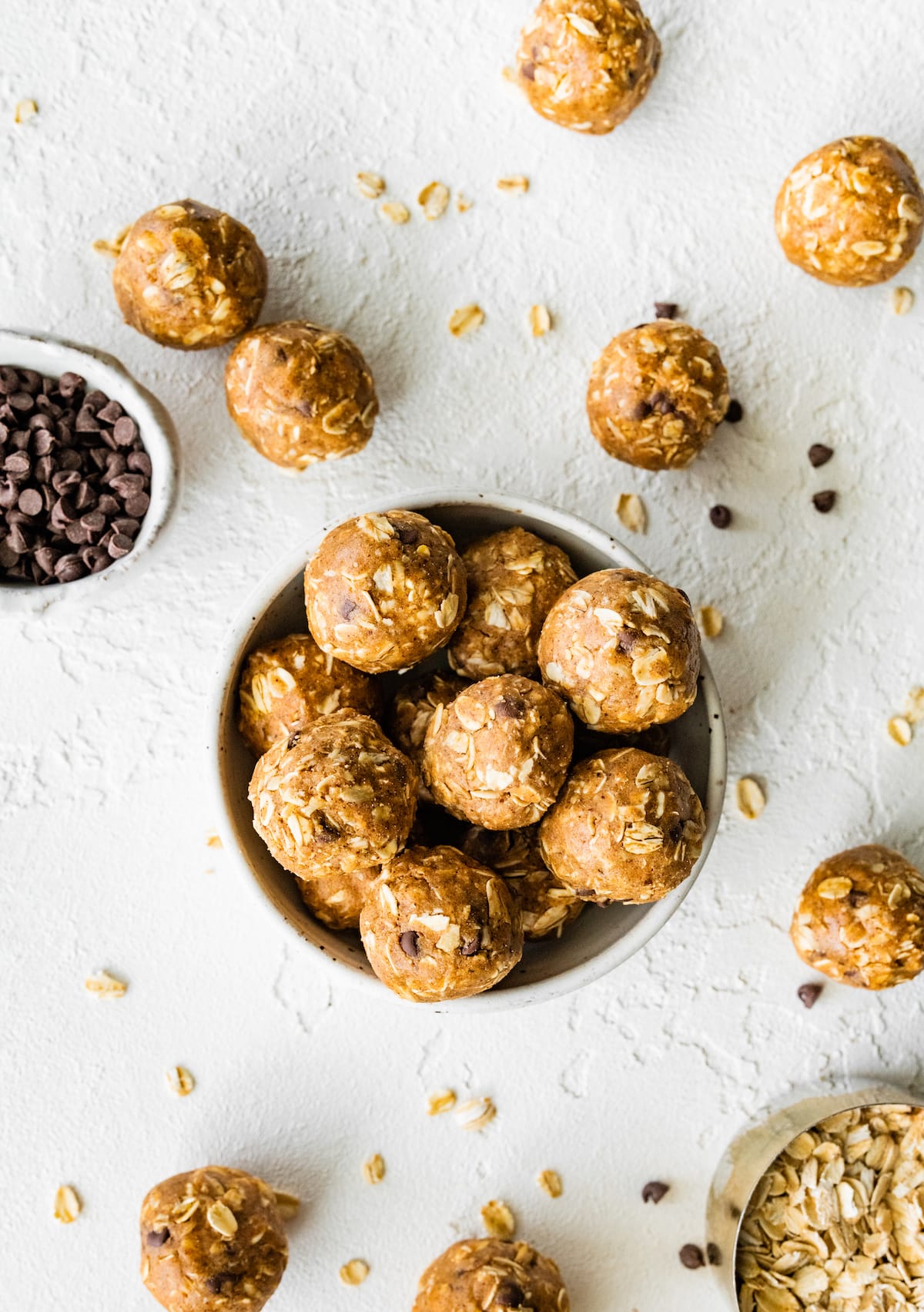 Vegan protein balls in a small bowl with some scattered on a table.