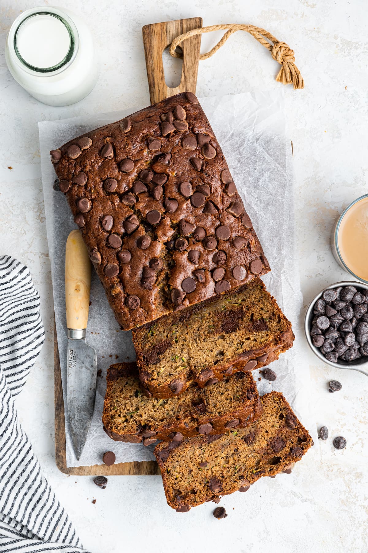 A loaf of zucchini banana bread on a wooden cutting board with three slices cut from it.