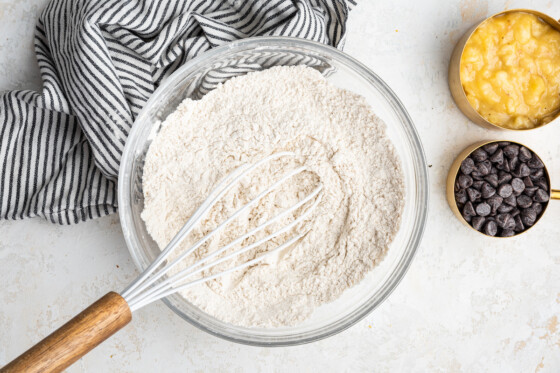 White flour in a large glass bowl with a whisk.