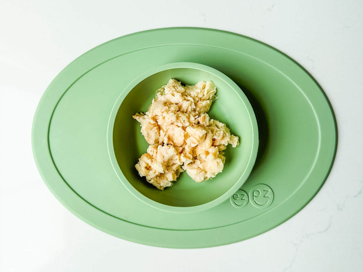 Mashed white beans in a green ezpz baby bowl.