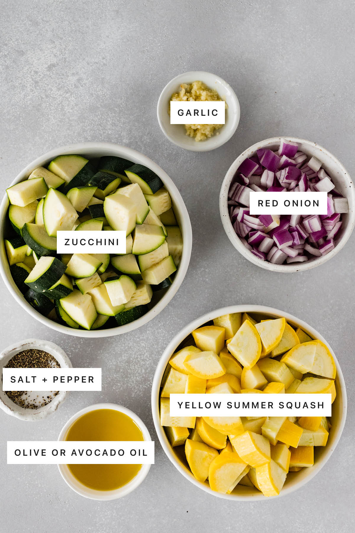Ingredients measured out to make Roasted Zucchini and Squash: garlic, red onion, zucchini, salt, pepper, yellow summer squash and olive oil.