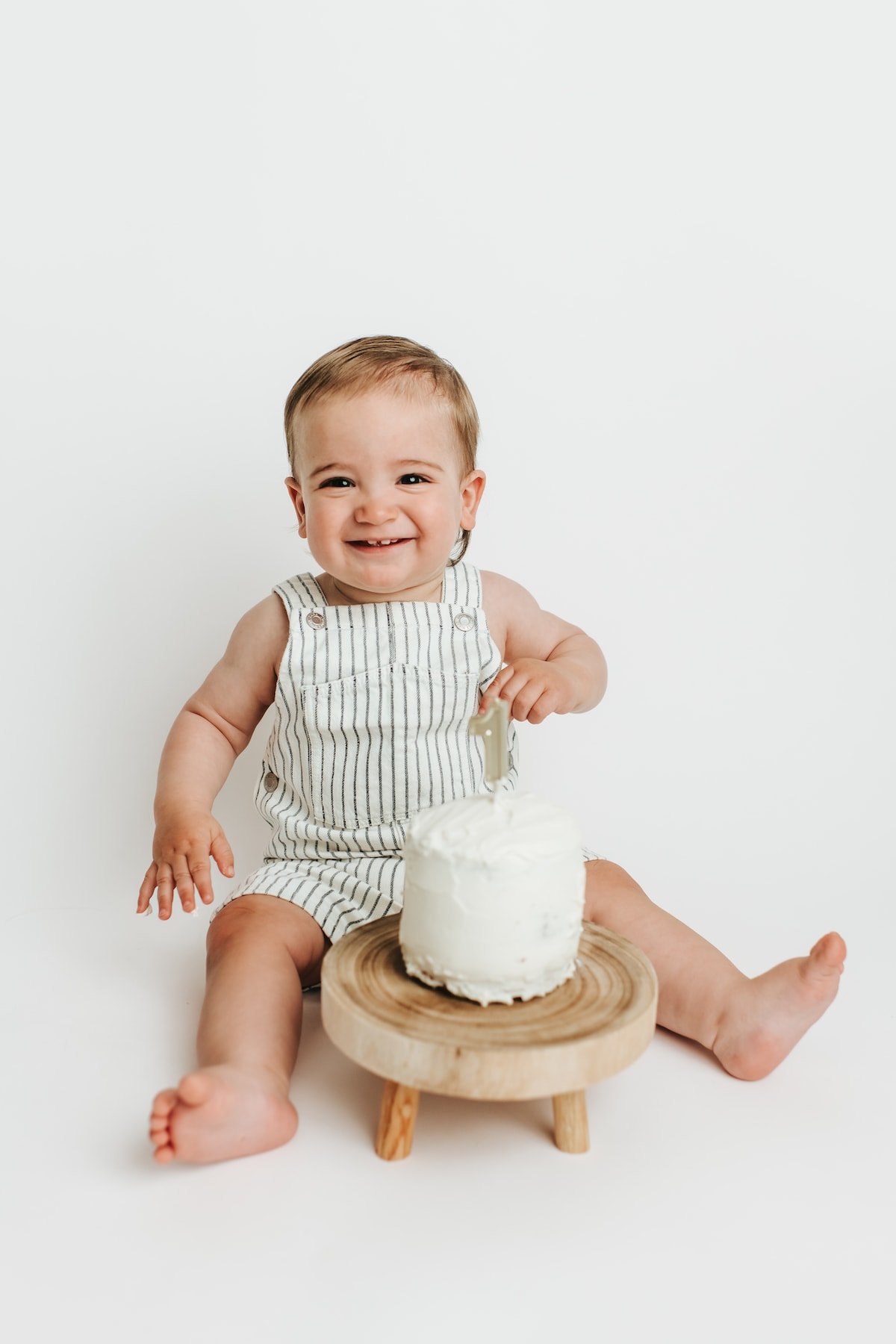 Baby Boy with small sash cake in front of him with a one candle in it.