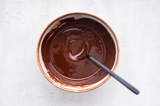 A bowl with a spoon and melted chocolate.