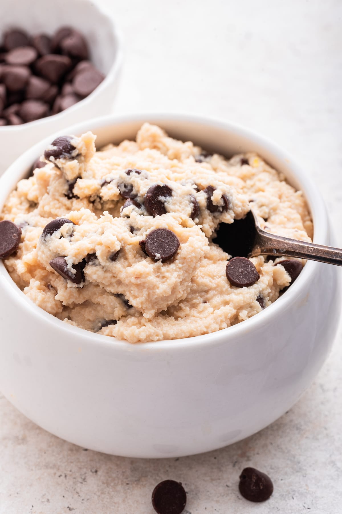 A spoon in a small bowl of cottage cheese cookie dough.