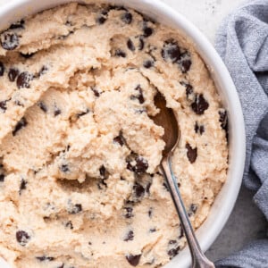 A spoon in a white bowl of cottage cheese cookie dough.