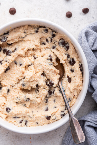 A spoon in a white bowl of cottage cheese cookie dough.