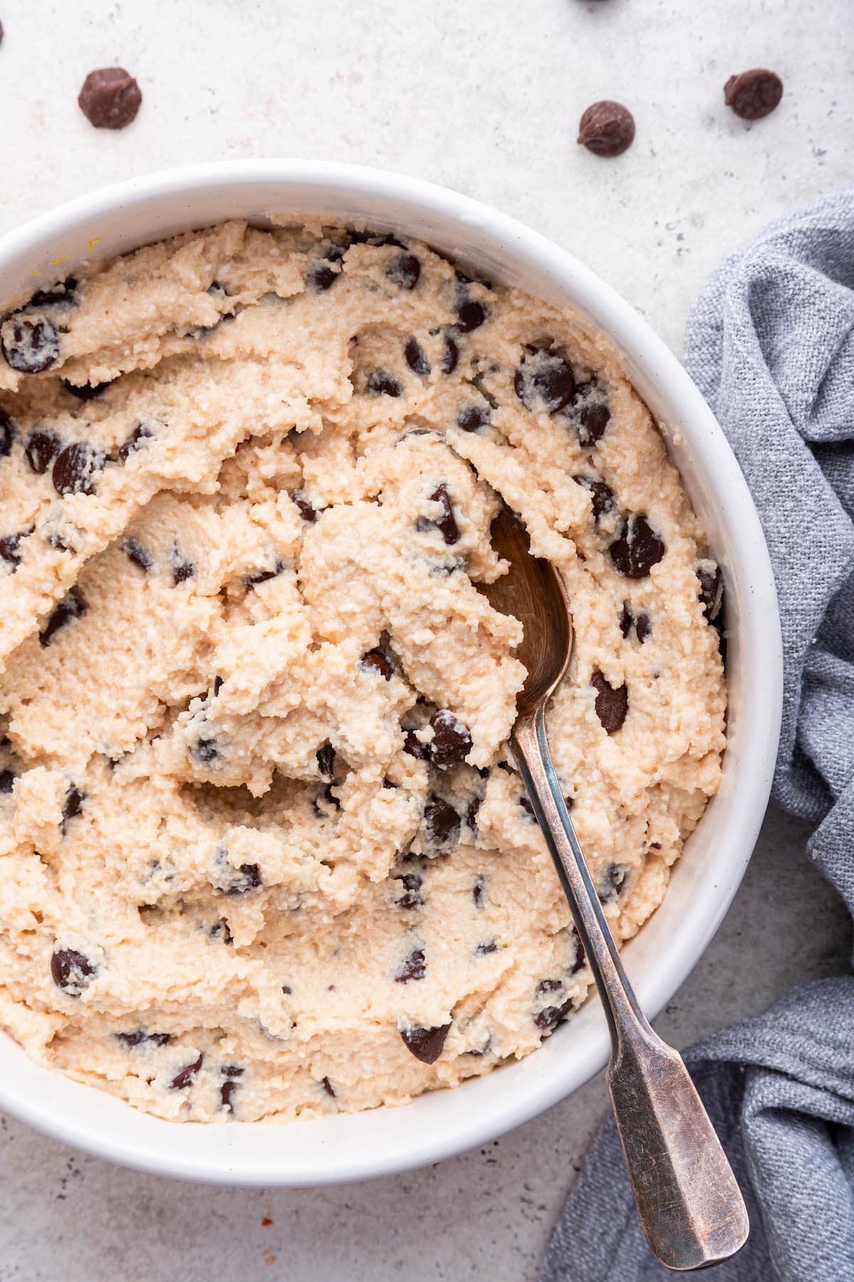 A spoon in a white bowl of cottage cheese cookie dough.