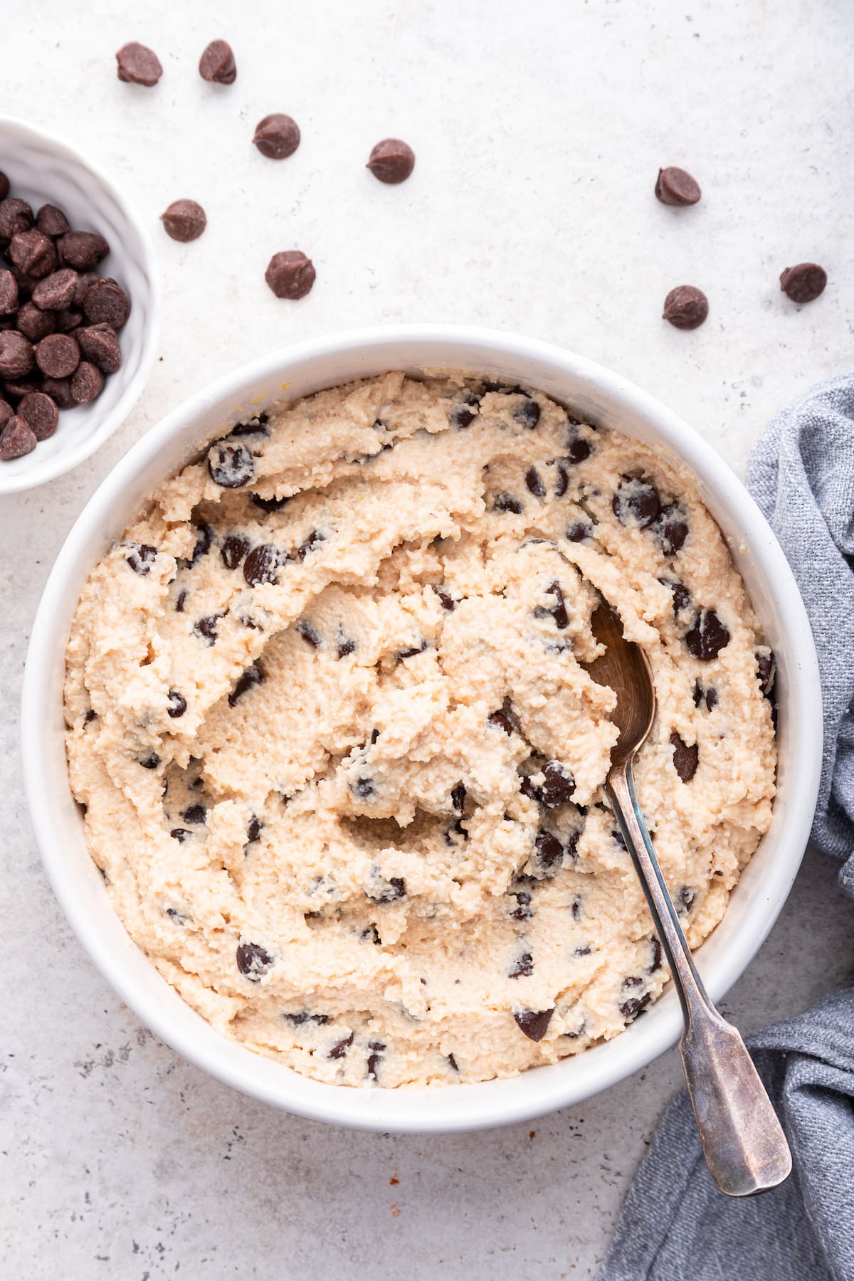 A spoon in a white bowl of cookie dough with cottage cheese.