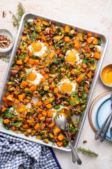 Sweet potato hash on a baking tray with two metal spoons.