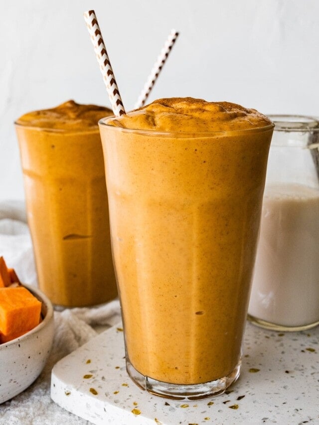 Two glasses with a sweet potato smoothie, straws, and topped off with ground cinnamon.