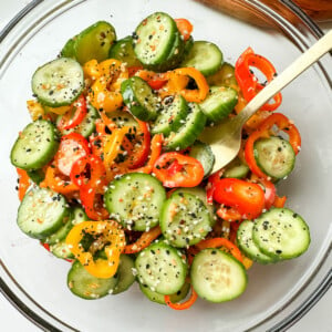 Cucumber and bell pepper salad in a clear mixing bowl.
