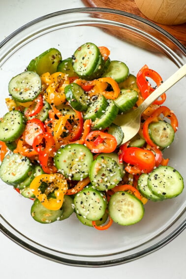 Cucumber and bell pepper salad in a clear mixing bowl.