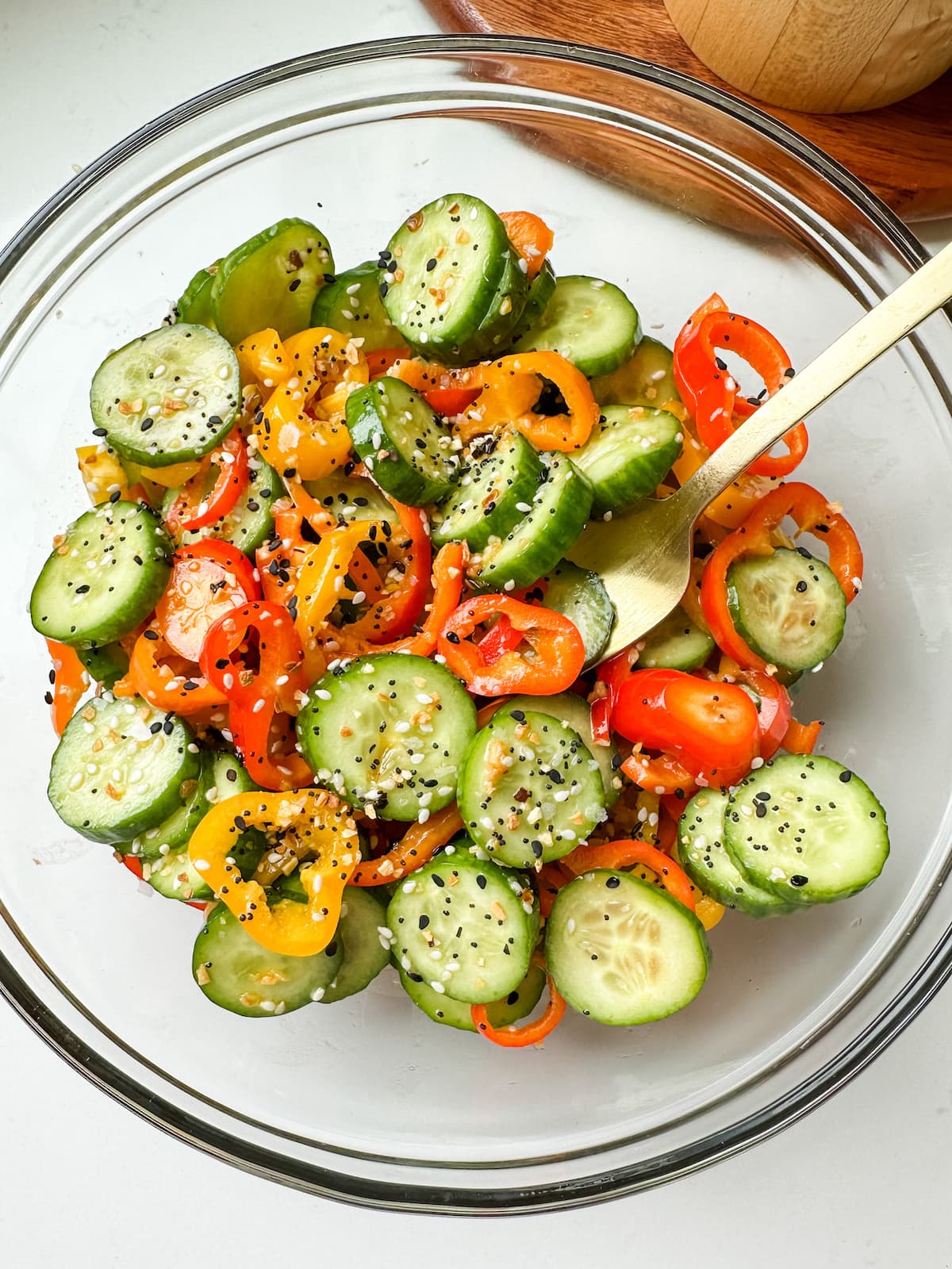 Cucumber and bell pepper salad in a clear mixing bowl.