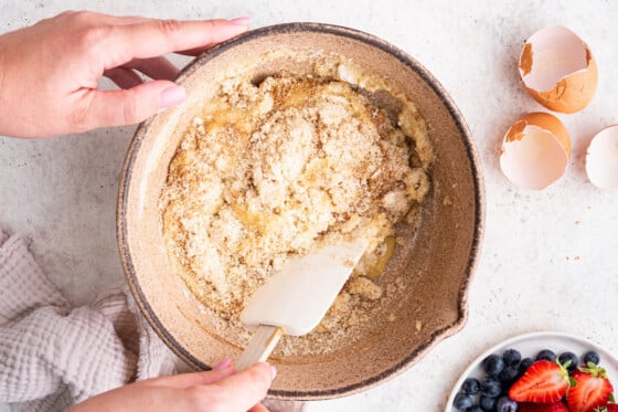 Woman's hands mixing the smash cake ingredients together with a spatula.