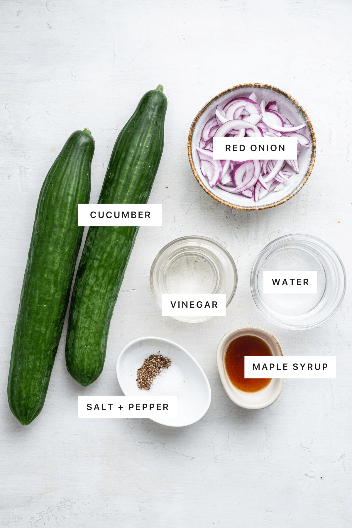 Measured ingredients to make Easy Cucumber Salad: cucumber, red onion, vinegar, water, salt, pepper, and maple syrup.
