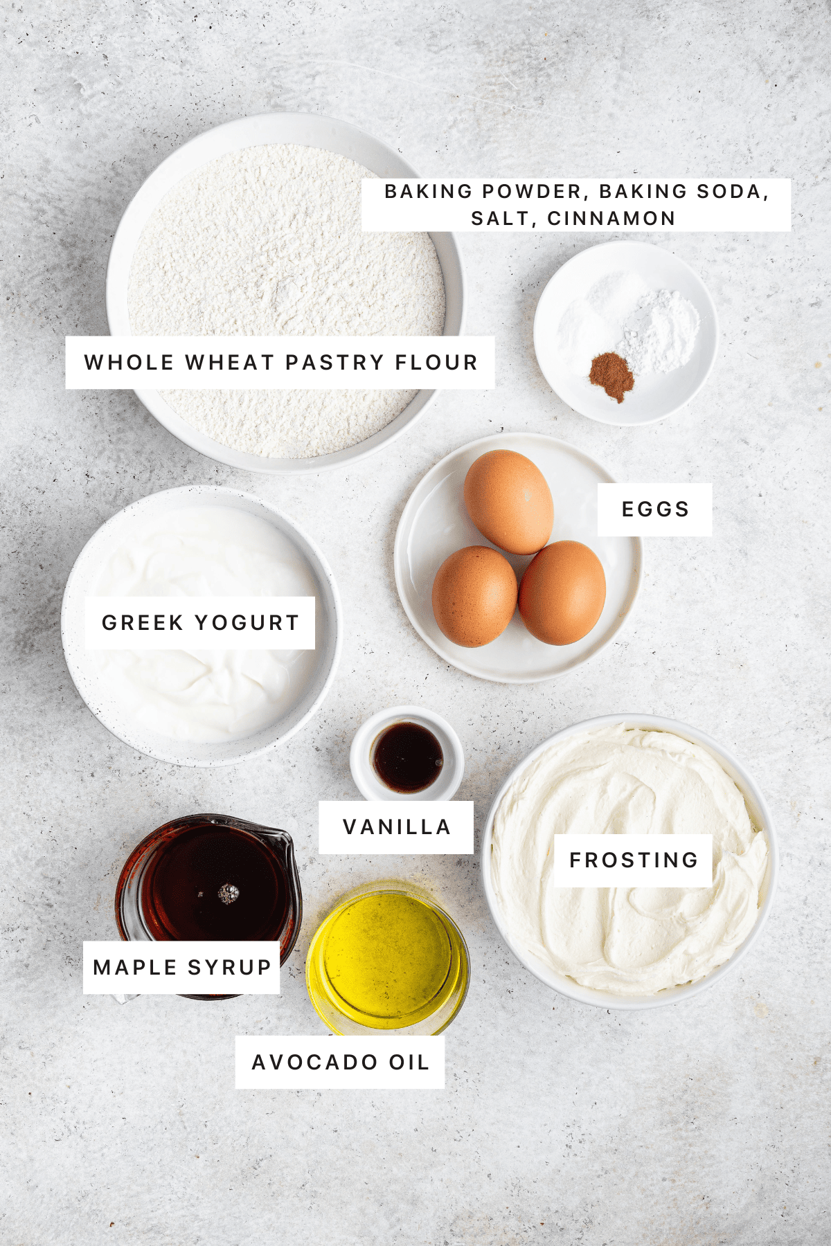 Ingredients for the healthy vanilla cake: whole wheat pastry flour, baking soda, baking powder, salt, cinnamon, eggs, greek yogurt, vanilla, maple syrup, avocado oil and frosting.