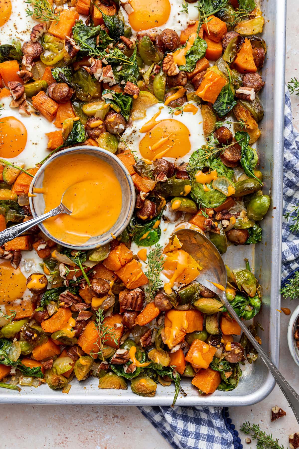 Sweet potato hash on a baking tray with a small bowl of sauce.