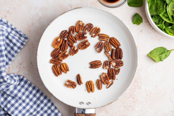 Pecans in a white skillet.