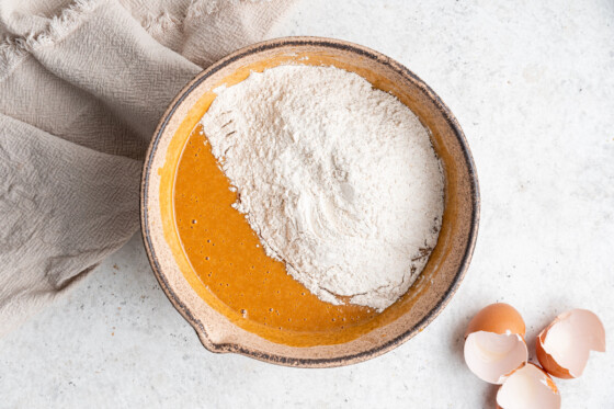 Wet and dry ingredients being combined in a large mixing bowl for the sweet potato muffins.