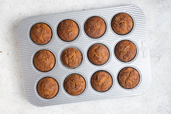 Twelve sweet potato muffins in a muffin tin after being baked.