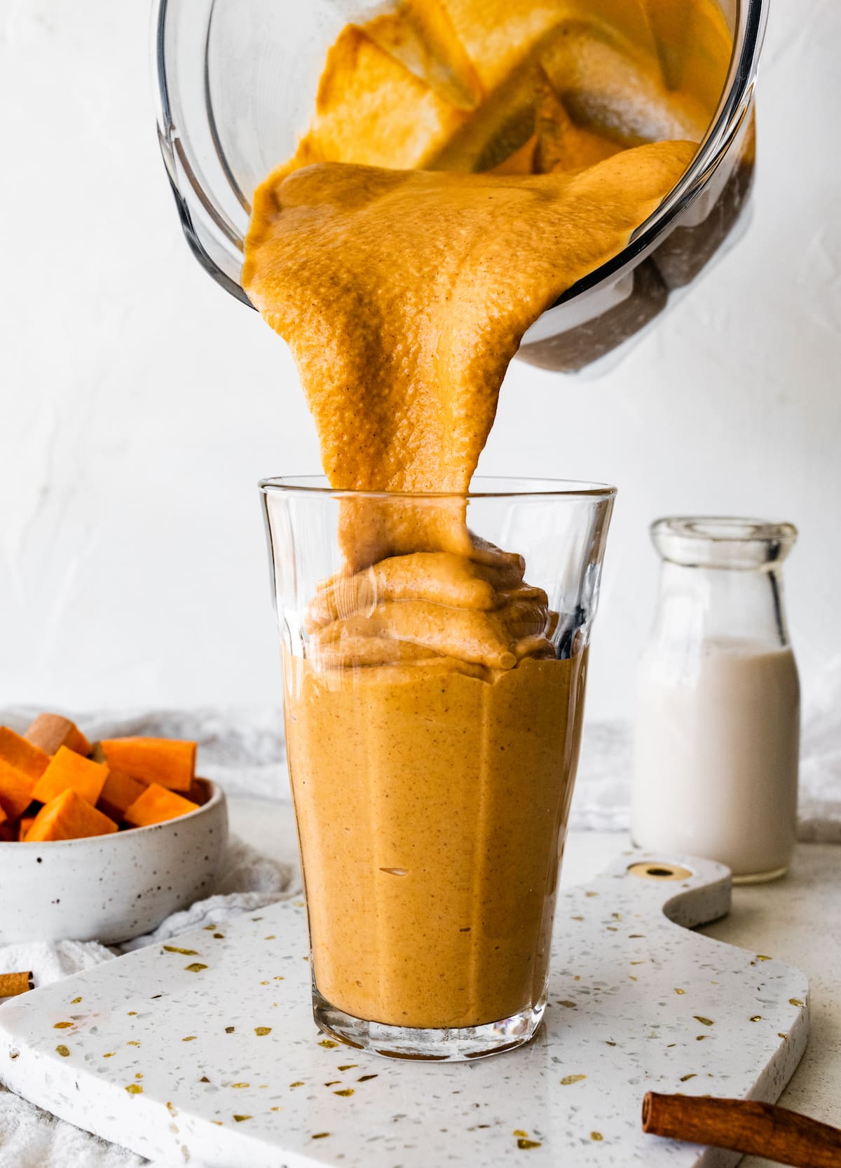 Sweet potato smoothie in a blender being poured into a glass.