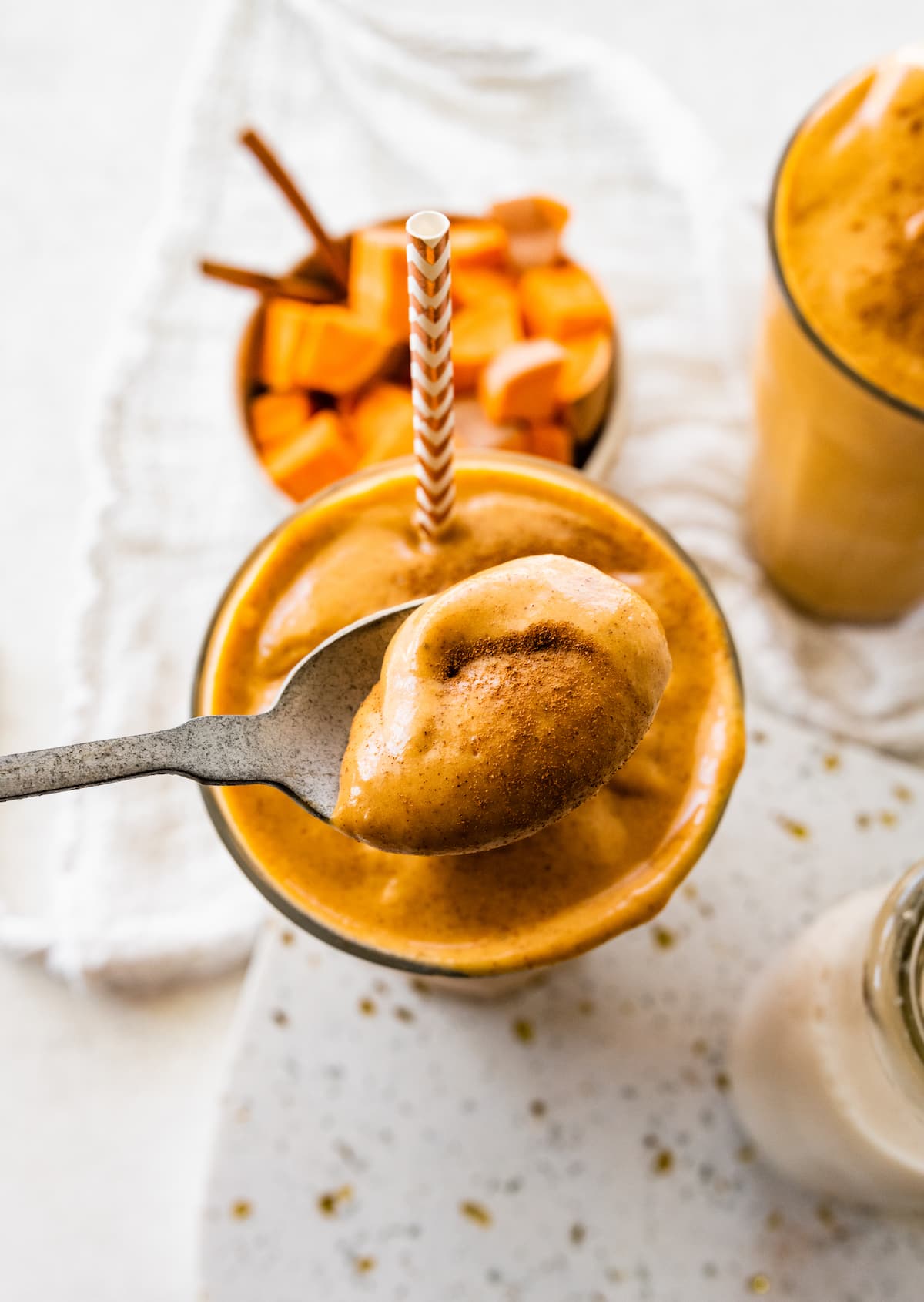 A spoonful of sweet potato smoothie over a glass of the smoothie.