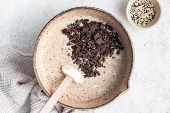 Chocolate chips added to a large mixing bowl with the tahini baked oatmeal mixture.