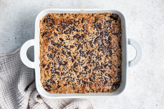Tahini baked oatmeal topped with chocolate chips in a square baking dish after being baked.