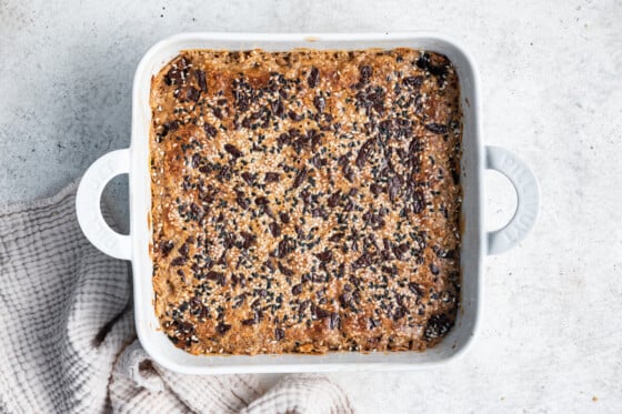 Tahini baked oatmeal topped with chocolate chips in a square baking dish after being baked.