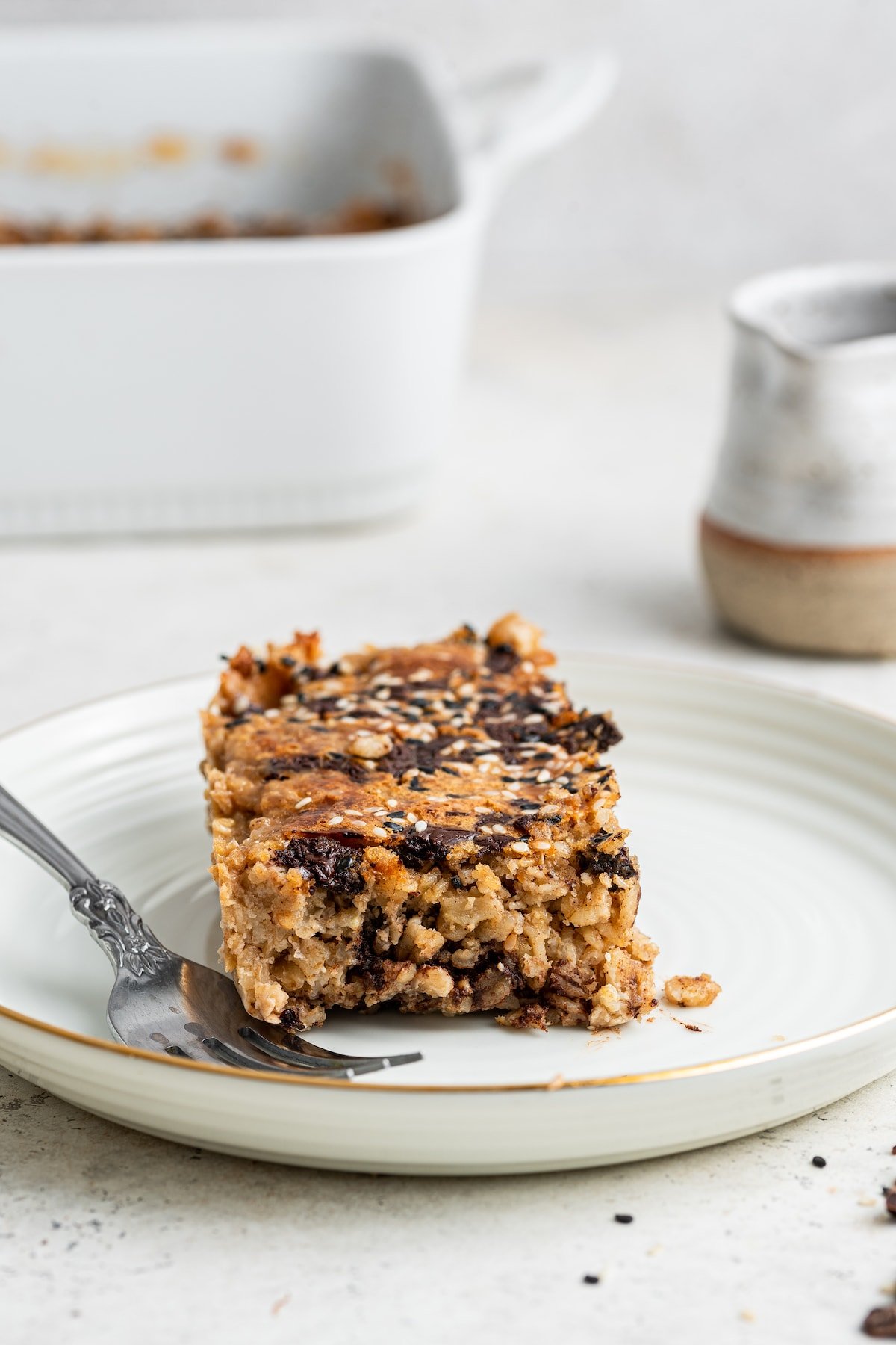 A piece of tahini baked oatmeal on a white plate with a fork.