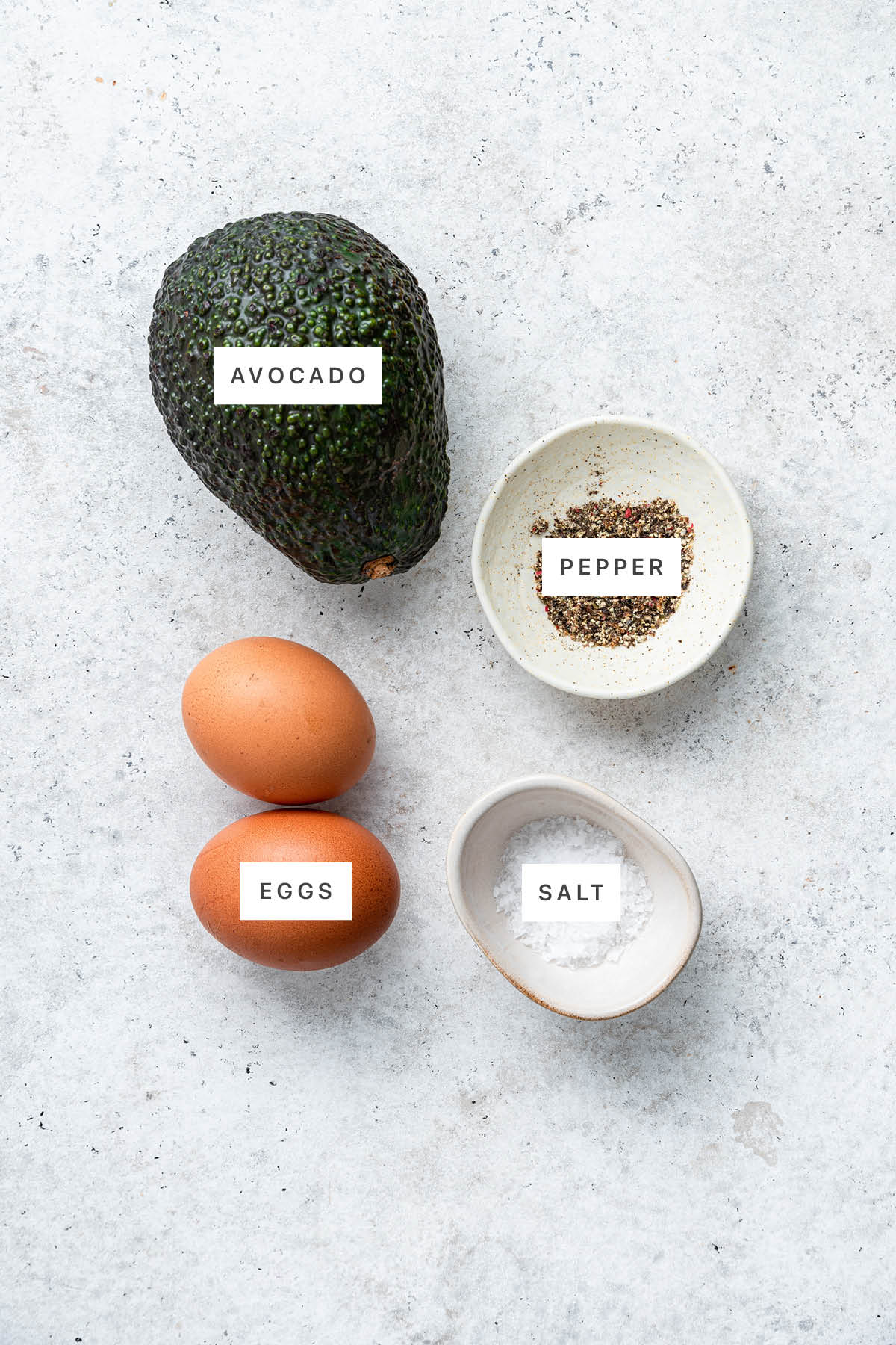 Ingredients measured out to make Baked Avocado Eggs: avocado, pepper, eggs and salt.