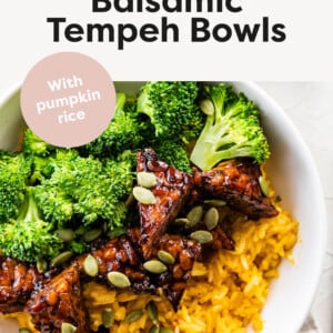 A white bowl with maple balsamic tempeh, broccoli, pumpkin seeds, and pumpkin rice.